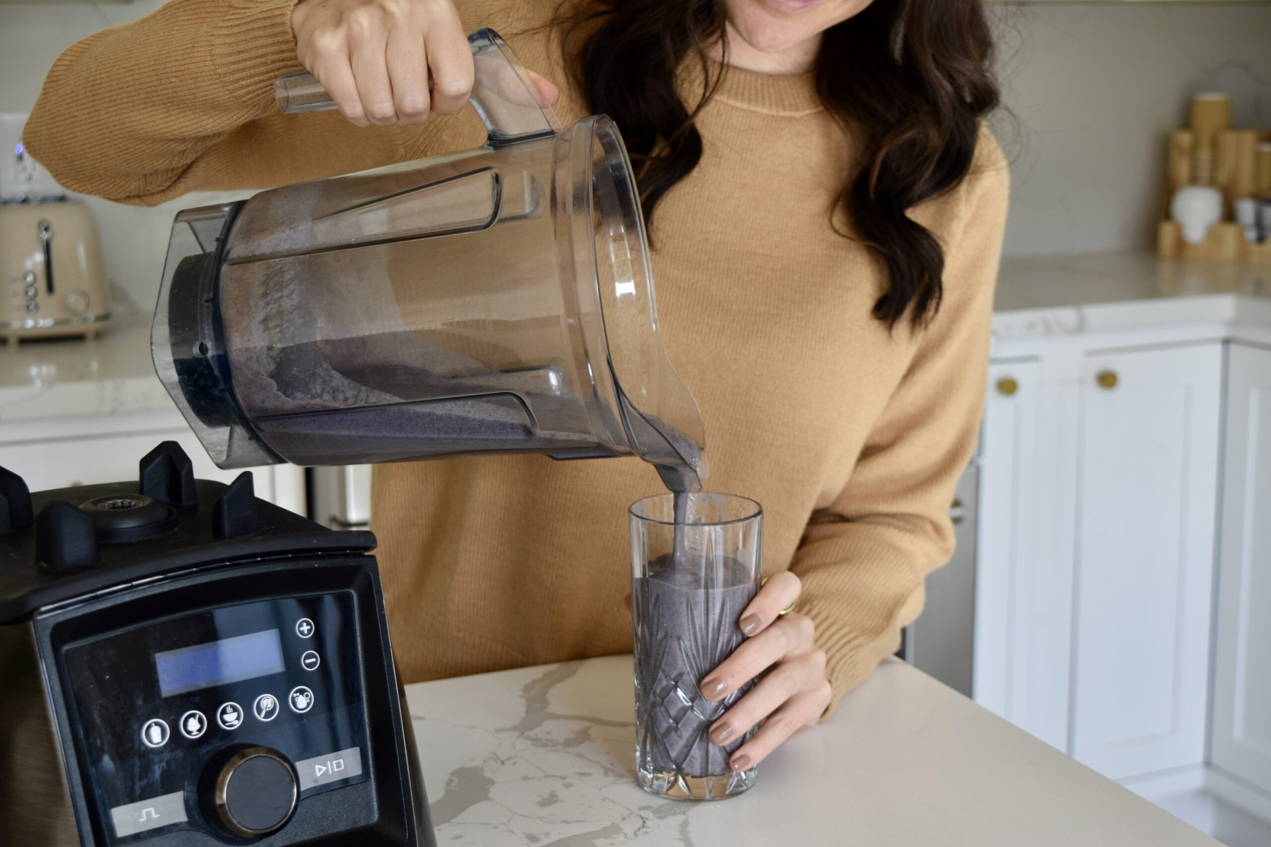 Woman pouring purple smoothie into glass.