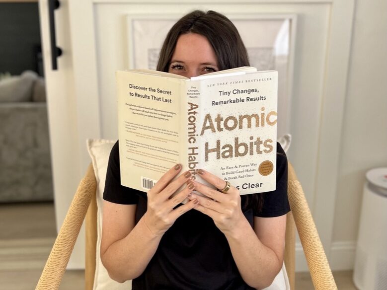 Girl holding the book Atomic Habits by James Clear.